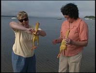 Libby and Debbie, standing at the water's edge holding rubber chickens.