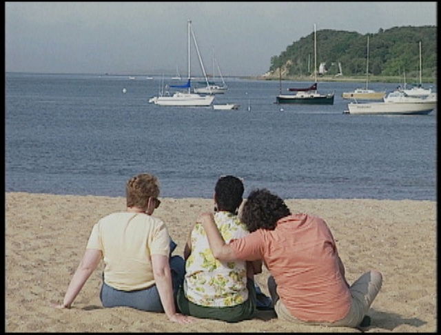 All
three, sitting on the sand facing the water, backs to us.