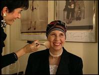 Libby wears a turban and smiles as makeup is brushed onto her face.