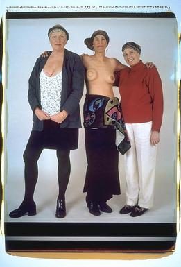 All three.  Debbie is exposing a scar on her right breast, just above the neckline of a low cut blouse.  Carol is without a shirt, to expose her reconstructed right breast. Libby is wearing a red turtleneck. 